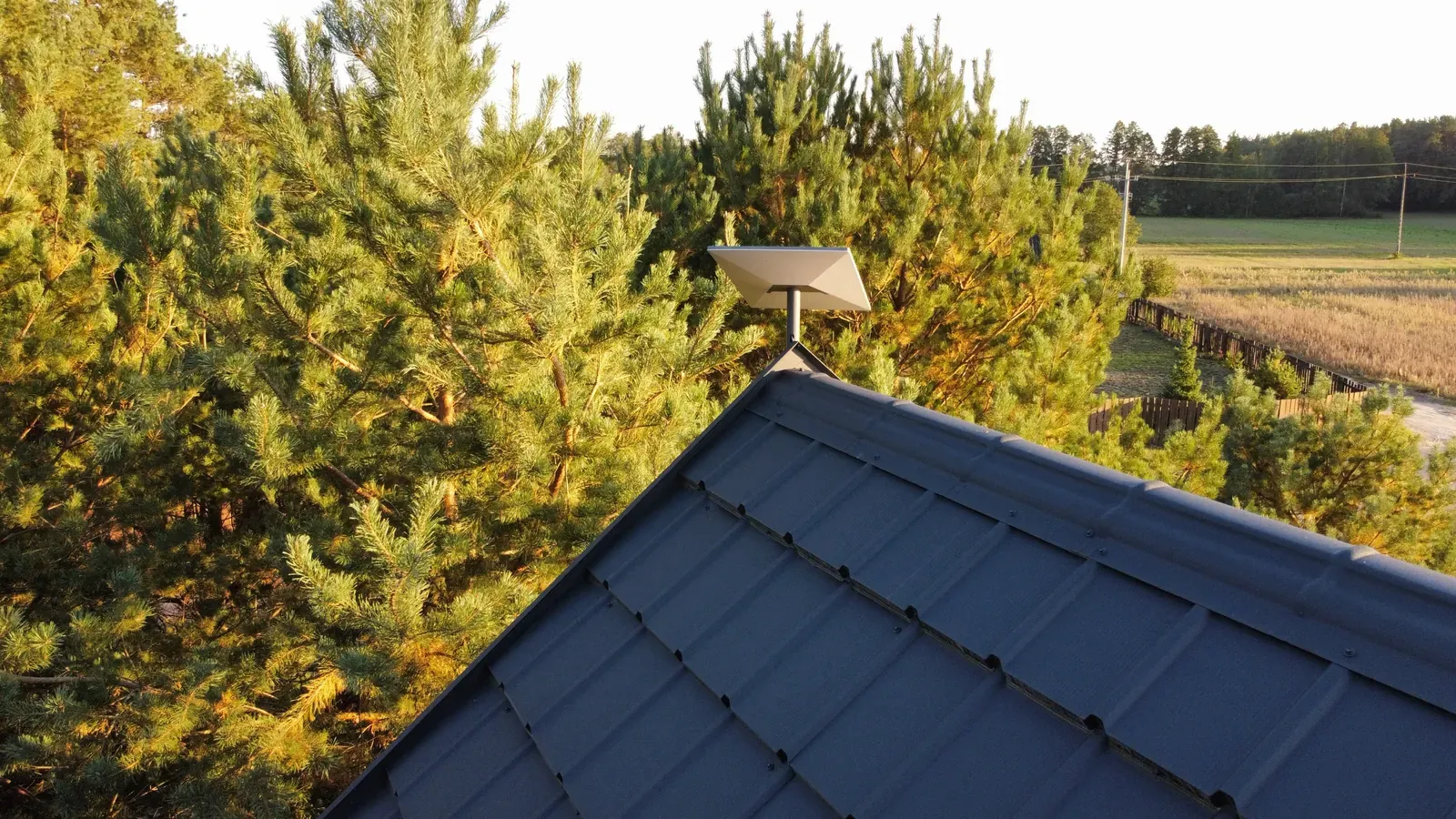 Antena Starlink na szczycie dachu z widokiem na pole