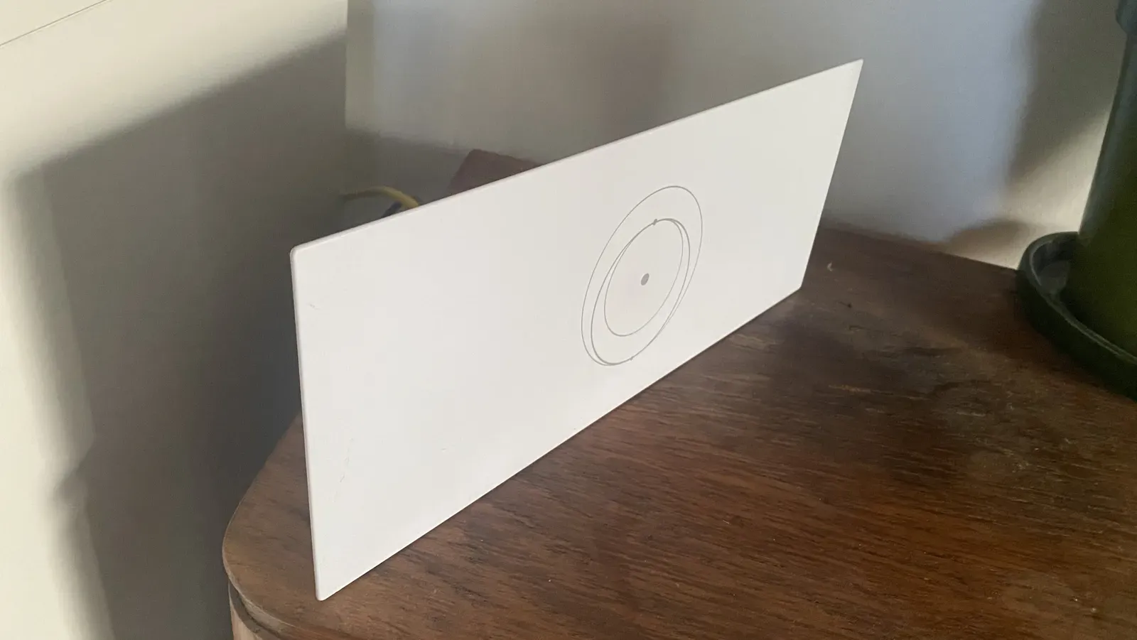 Router Starlink widziany z boku, cienki biały panel na drewnianej komodzie