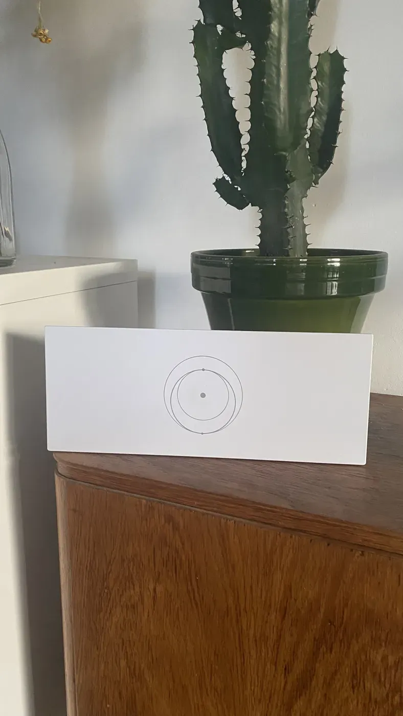 Router Starlink Standard stojący pionowo na komodzie, z wygrawerowanym symbolem orbity